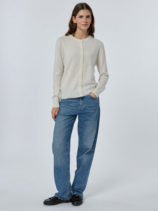 Woman wearing a beige cardigan and blue jeans on a white background cream
