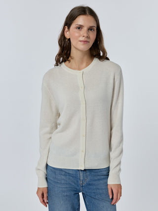 Woman wearing a beige cardigan and blue jeans on a white background cream
