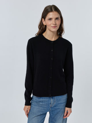 Woman wearing a black cardigan and blue jeans on a light gray background Black