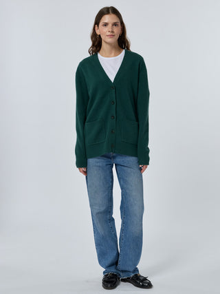 Person wearing a green cardigan, white shirt, blue jeans, and black shoes on a white background - Hunter