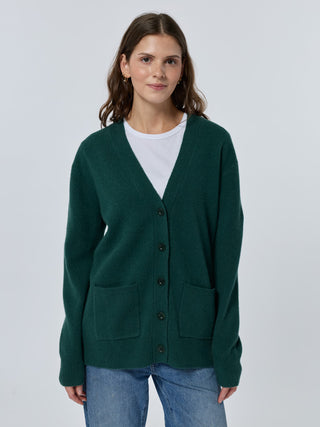 Woman wearing a green cardigan over a white shirt on a light gray background - Hunter
