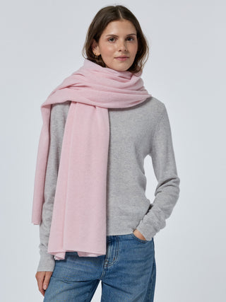 Woman wearing a pink scarf, gray sweater, and blue jeans on a white background Pale pink