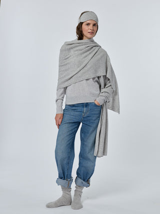 Person wearing a gray sweater, blue jeans, and gray socks on a white background smoke