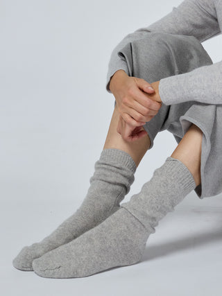 Person wearing gray socks and pants on a light gray background smoke